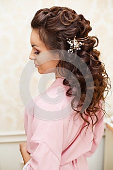 Beautiful young Bride with dark hairs sits on a sofa in a bedroom. Bride`s morning.