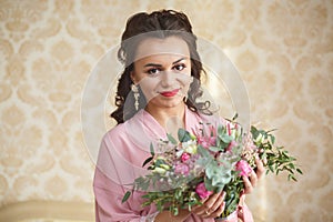 Beautiful young Bride with dark hairs sits on a sofa in a bedroom. Bride`s morning.