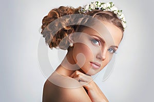 Beautiful young bride with a floral ornament in her hair.Beautiful Woman Touching her Face. Youth and Skin Care Concept on white