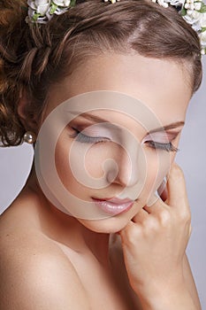 Beautiful young bride with a floral ornament in her hair.Beautiful Woman Touching her Face. Youth and Skin Care Concept on white