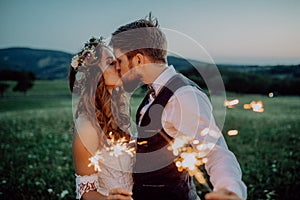 Beautiful bride and groom with sparklers on a meadow.