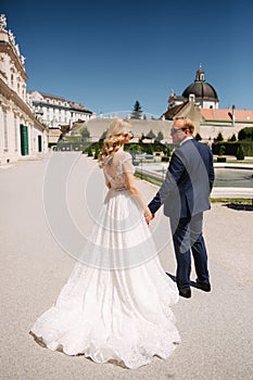 Beautiful young bride with her handsome groom walking in palace Belvedere