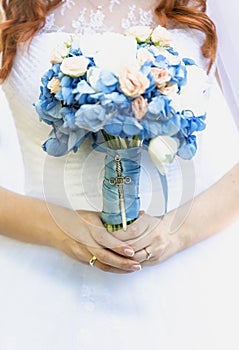 Beautiful young bride holding bridal bouquet of blue flowers