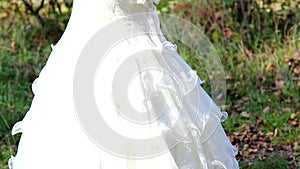Beautiful young bride is holding wedding bouquet in hands and standing outdoors over beautiful sunny nature background