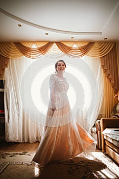Beautiful young bride near the window in full growth