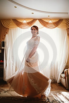 Beautiful young bride near the window in full growth