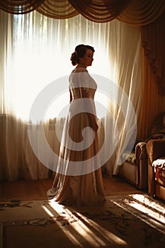 Beautiful young bride near the window in full growth