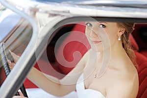 Beautiful young bride portrait in a wedding car