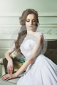 Beautiful Young Bride Sensualy Posing On Sofa. White Wedding Dress