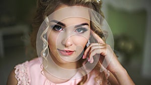 Beautiful Young Bride. Stylish Woman Fiancee with Bridal Hairstyle, Event Makeup and Jewelry. He looks up at the camera.