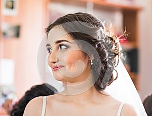 Beautiful young bride with wedding makeup and hairstyle in bedroom, newlywed woman final preparation for wedding. Happy