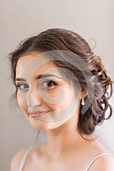 Beautiful young bride with wedding makeup and hairstyle in bedroom, newlywed woman final preparation for wedding. Happy