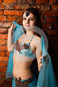 Beautiful young brunette in a blue suit oriental dance over a br