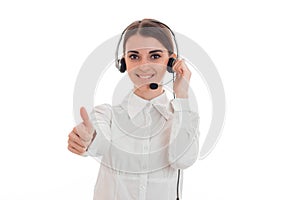 Beautiful young brunette business woman with headphones and microphone showing thumbs up and smiling isolated on white