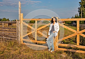 Beautiful young caucasian woman standing at the ranch gate