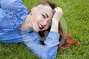Beautiful young brunette girl on a green grass
