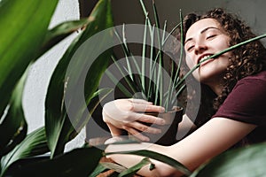Beautiful young brunette girl with a green plant in pot