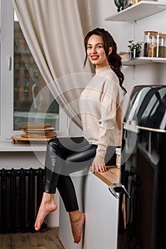 beautiful young brunette girl in the kitchen in a sweater. beautiful smile