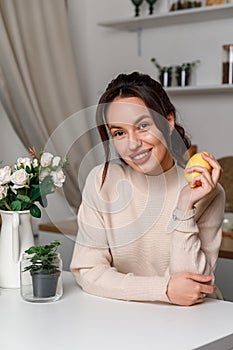 beautiful young brunette girl in the kitchen in a sweater with lemon. beautiful smile