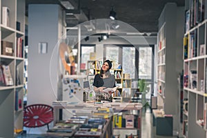 Beautiful young brunette posing in a bookstore