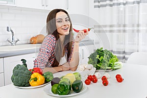 Beautiful Young Brunette Posing in a Kitchen Full of Greengrocery photo