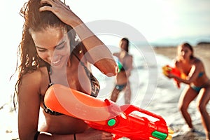 Beautiful young brunette trying to hide her face from water splash of  water guns