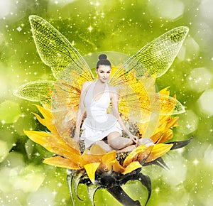 Beautiful young brunette woman as summer fairy on sunflower