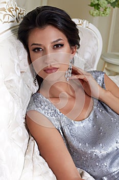 beautiful young brunette woman with evening make-up chic groomed wearing a short evening dress embroidered with silver