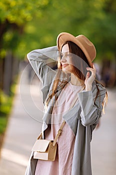 Beautiful young brunette woman with long hair flying in the wind and brown hat in park in summer. Head shot of gorgeous