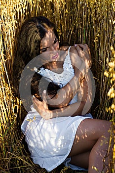 Beautiful young brunette woman lying on wheat in field