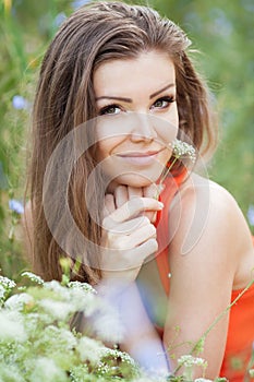 Beautiful young brunette woman on the meadow with white flowers on a warm summer day