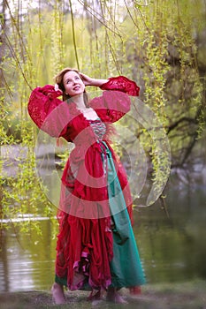 Young  brunette woman in red gown walking barefoot in nature