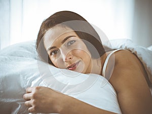 Beautiful young brunette woman sleeping while lying in bed comfortably and blissfully. Good morning concept