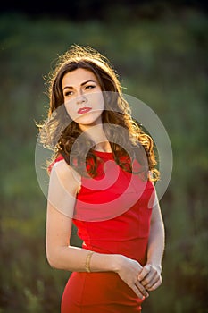 Beautiful young brunette woman standing against green grass background