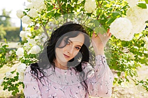 beautiful young brunette woman in white flowers on a warm summer day