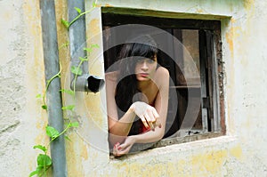 Beautiful young brunette woman in the window