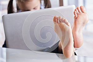 Beautiful young business girl working in office, feet on desk. Selective focus on feet. Copy space