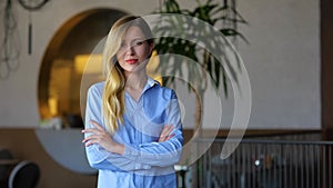 Beautiful young business lady looking at camera and smiling while standing indoors. Portrait of joyful pretty woman in