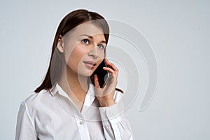 Beautiful young business lady woman in white shirt with serious expression talking on the phone. Close-up