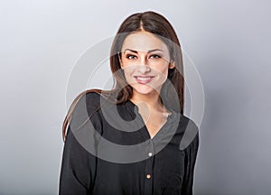 Beautiful young business toothy smiling woman thinking and looking happy on blue grey background with empty copy space. Portrait