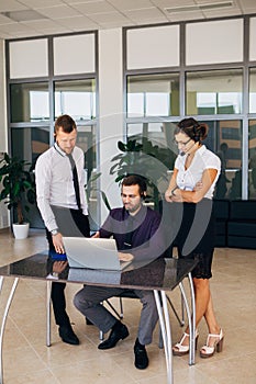 Beautiful young business woman and businessmans in headsets using laptops while working in office