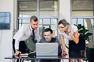 Beautiful young business woman and businessmans in headsets using laptops while working in office