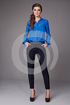 Beautiful young business woman with evening make-up dressed in tight pants and silk blouse with lace long sleeves and high-he