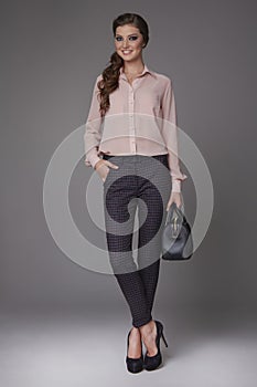 Beautiful young business woman with evening make-up dressed in tight pants and silk blouse with lace long sleeves and high-he
