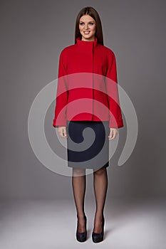 Beautiful young business woman with evening make-up wearing a dark skirt to the knee wool red coat jacket high boots high hee
