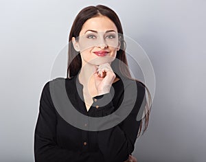 Beautiful young business woman thinking and looking up on blue background