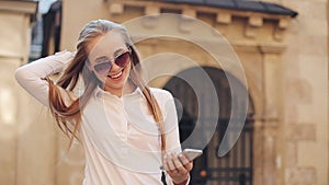 Beautiful young business woman wearing white shirt and using smartphone while walking in the city center summer internet