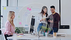 Beautiful young business woman working with computer while her colleagues having a break in modern startup office.