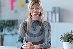 Beautiful young business woman working with computer while smiling looking at camera in the office