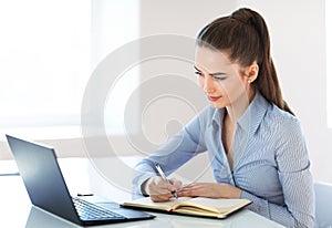 Beautiful young business woman writing in notebook